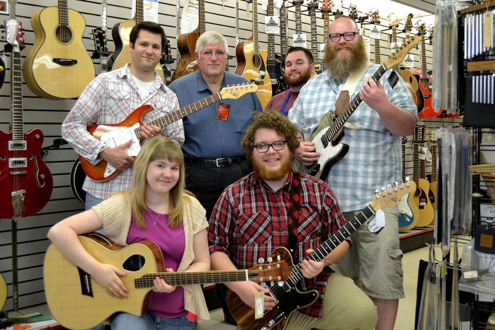 King Music Inc staff holding Michael Kelly electric guitars and acoustic guitars